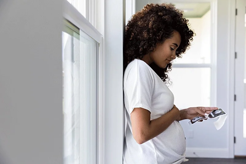 Pregnant woman looking at x-ray images while holding her tummy and smiling